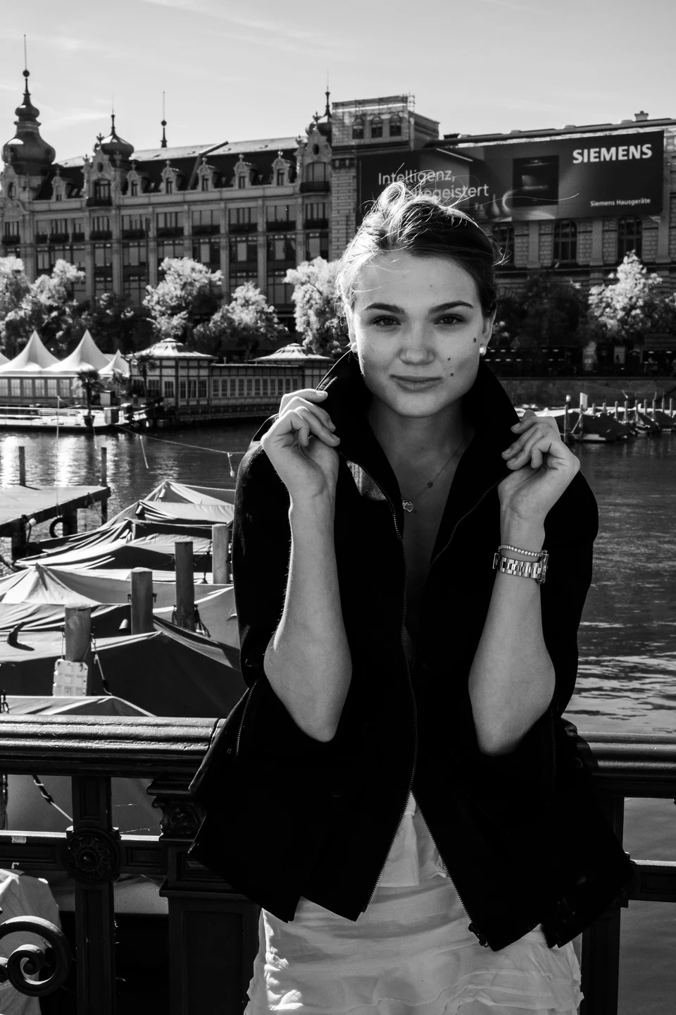 Black-and-white portrait leaning on a city bridge railing.