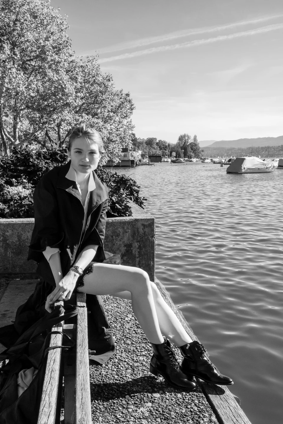 Portrait in a black jacket seated beside a lake.