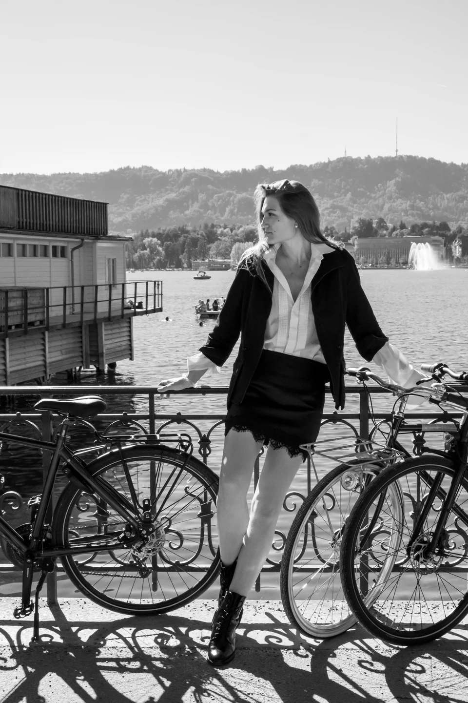 Fashion portrait beside bicycles at a lakeside railing.