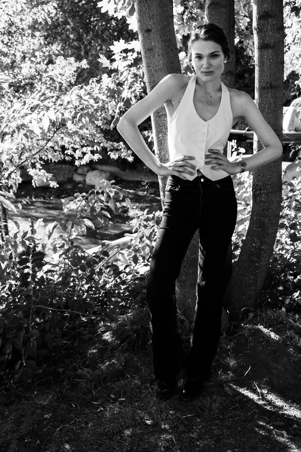 Monochrome standing portrait in a light blouse framed by leaves.