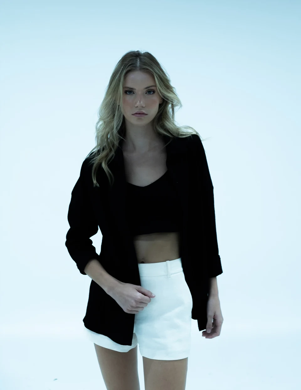 Studio fashion portrait in a black jacket and white shorts.